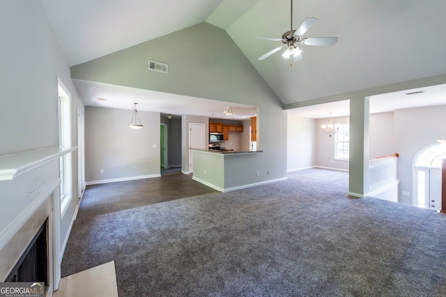 unfurnished living room with ceiling fan with notable chandelier, dark colored carpet, and high vaulted ceiling