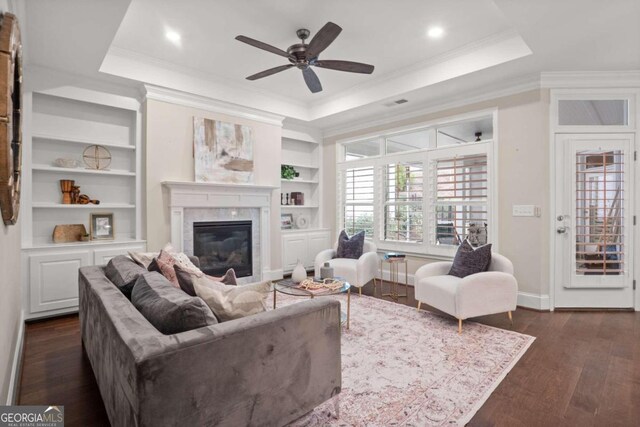 living room with a raised ceiling, crown molding, dark hardwood / wood-style flooring, and ceiling fan