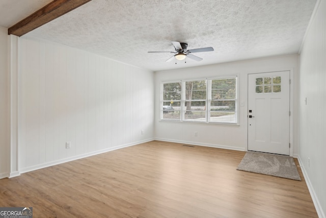 foyer entrance featuring a textured ceiling, light hardwood / wood-style floors, ceiling fan, and beam ceiling