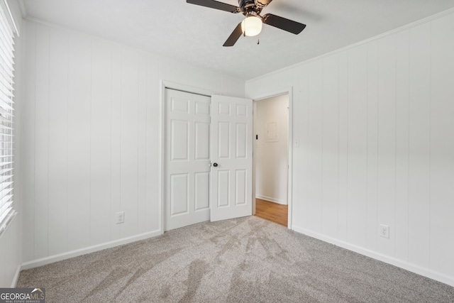 unfurnished bedroom featuring a closet, multiple windows, light carpet, and ceiling fan