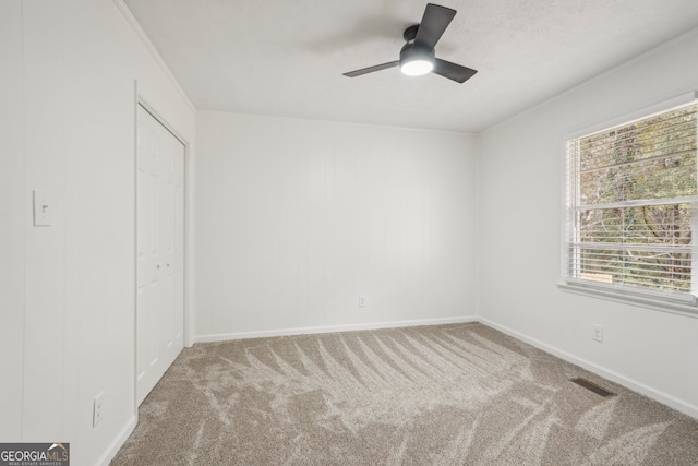 unfurnished bedroom with ornamental molding, carpet floors, ceiling fan, and a closet