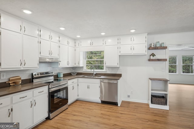 kitchen featuring stainless steel appliances, a wealth of natural light, white cabinets, and light hardwood / wood-style flooring