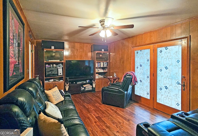 living room featuring hardwood / wood-style floors, ceiling fan, wooden walls, and crown molding