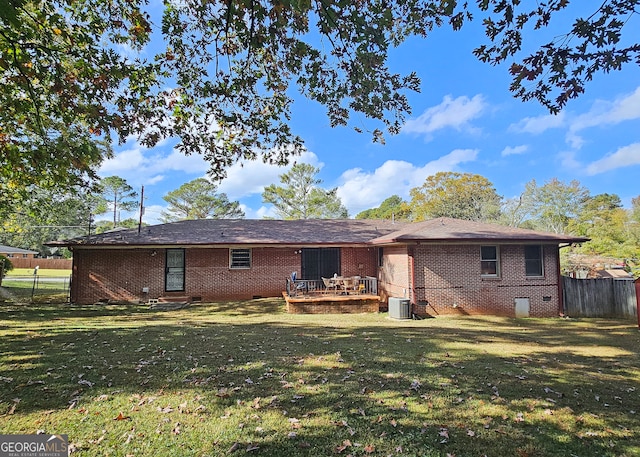 back of house with central AC unit and a yard