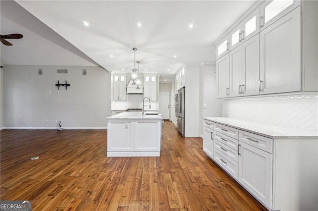 kitchen with white cabinetry, dark wood-type flooring, an island with sink, and hanging light fixtures