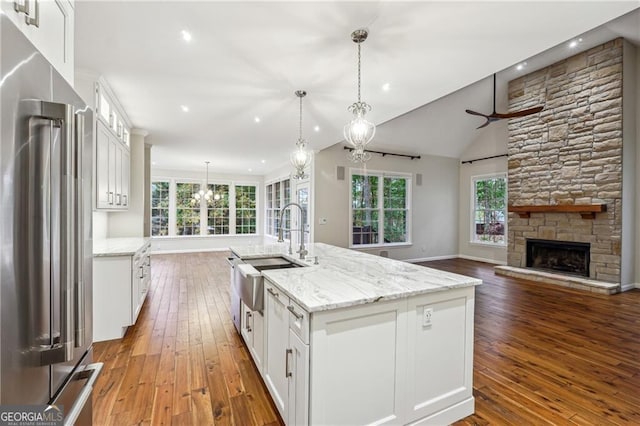 kitchen featuring white cabinets, a wealth of natural light, an island with sink, and high end refrigerator