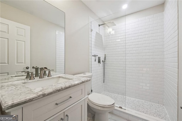 bathroom featuring a tile shower, vanity, and toilet