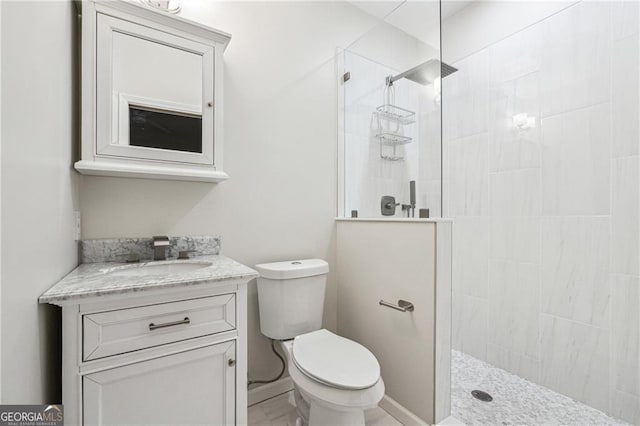 bathroom featuring toilet, vanity, and a tile shower