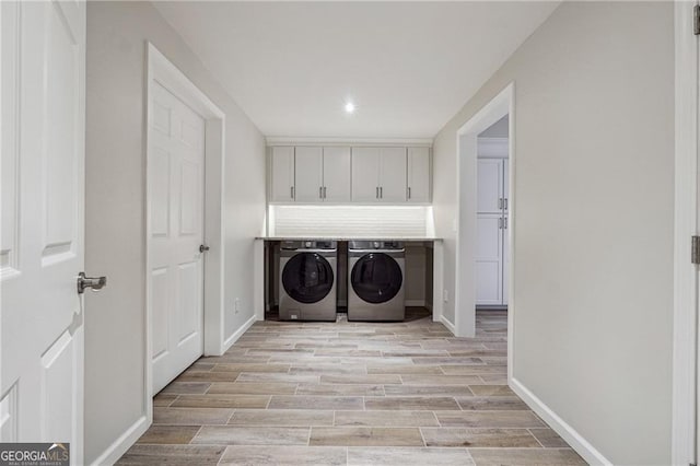 washroom with cabinets, washer and dryer, and light hardwood / wood-style flooring