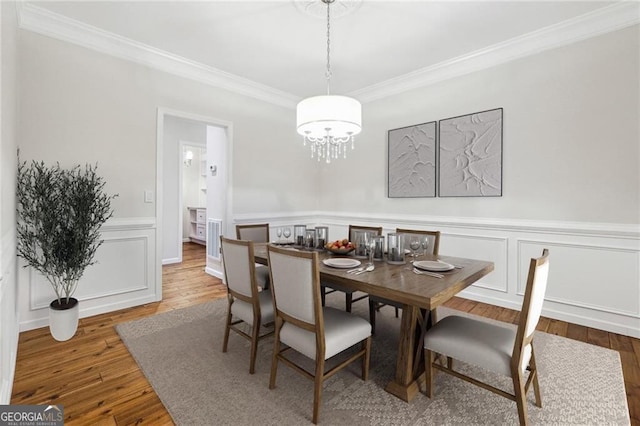 dining room featuring an inviting chandelier, hardwood / wood-style flooring, and ornamental molding