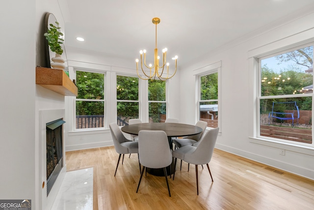 dining space featuring ornamental molding, sink, a large fireplace, and light hardwood / wood-style flooring