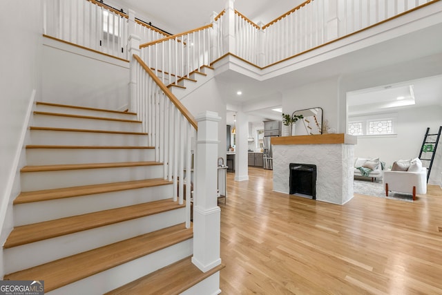 stairs with a towering ceiling, a fireplace, hardwood / wood-style flooring, and a tray ceiling