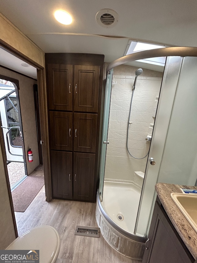 bathroom featuring walk in shower, hardwood / wood-style floors, vanity, and toilet