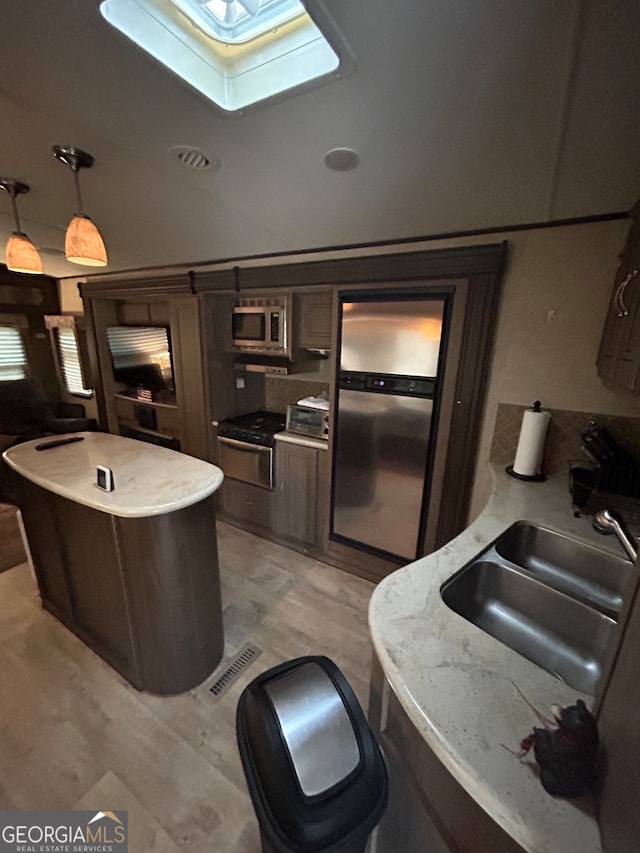 kitchen with light hardwood / wood-style flooring, sink, a skylight, dark brown cabinets, and appliances with stainless steel finishes