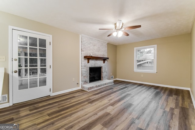 unfurnished living room with a brick fireplace, ceiling fan, a textured ceiling, and dark hardwood / wood-style flooring