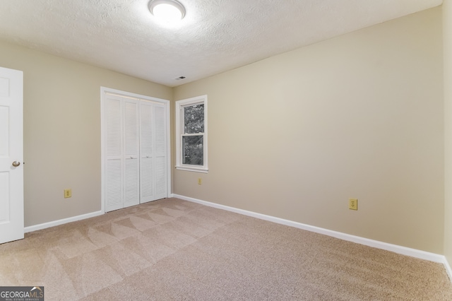 unfurnished bedroom with a closet, a textured ceiling, and light colored carpet