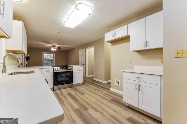 kitchen featuring kitchen peninsula, stainless steel range with electric stovetop, sink, white cabinetry, and light wood-type flooring