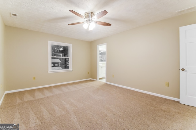 empty room with a textured ceiling, light carpet, and ceiling fan