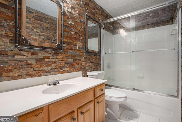 full bathroom with a textured ceiling, shower / bath combination with glass door, vanity, tile patterned floors, and toilet