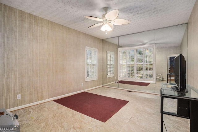 interior space with a textured ceiling and ceiling fan