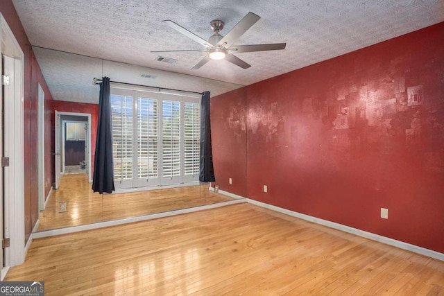 empty room featuring hardwood / wood-style flooring, ceiling fan, and a textured ceiling