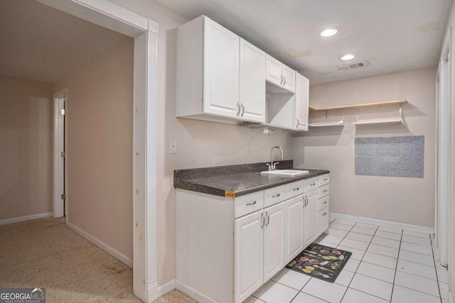 kitchen featuring light tile patterned floors, white cabinetry, and sink