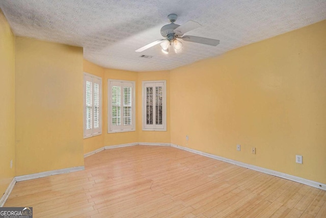 empty room with ceiling fan, a textured ceiling, and light wood-type flooring