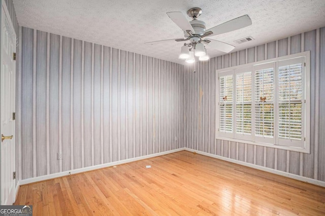 empty room featuring hardwood / wood-style floors, ceiling fan, and a textured ceiling