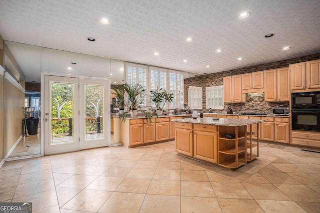 kitchen featuring light stone countertops, light brown cabinetry, black appliances, and a kitchen island