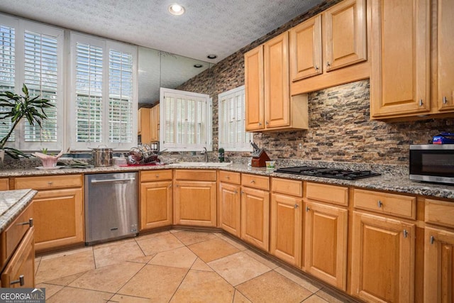 kitchen with stainless steel appliances, sink, light stone counters, a textured ceiling, and decorative backsplash