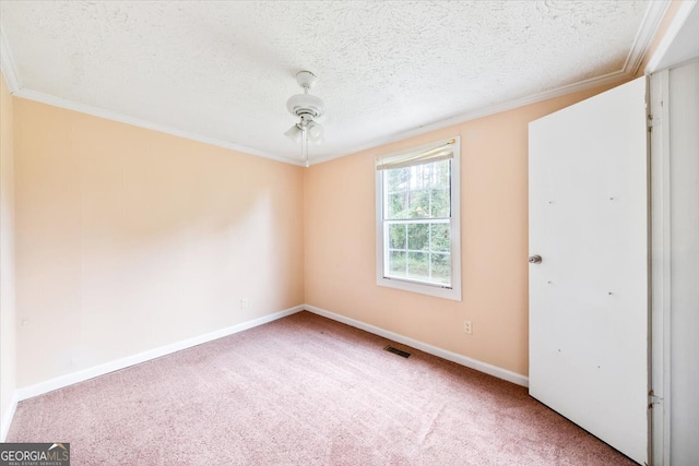 carpeted spare room with ceiling fan, a textured ceiling, and crown molding