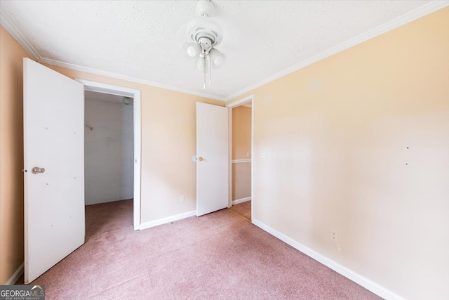 unfurnished bedroom with a closet, a walk in closet, light colored carpet, and ornamental molding