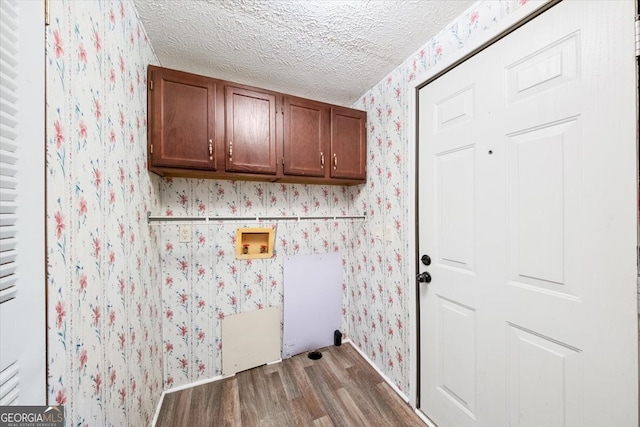 clothes washing area featuring hookup for a washing machine, cabinets, a textured ceiling, and dark hardwood / wood-style floors