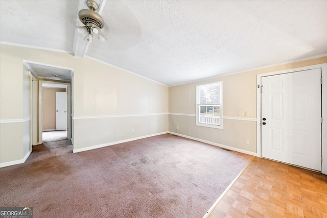 foyer entrance featuring a textured ceiling, lofted ceiling with beams, ornamental molding, and ceiling fan