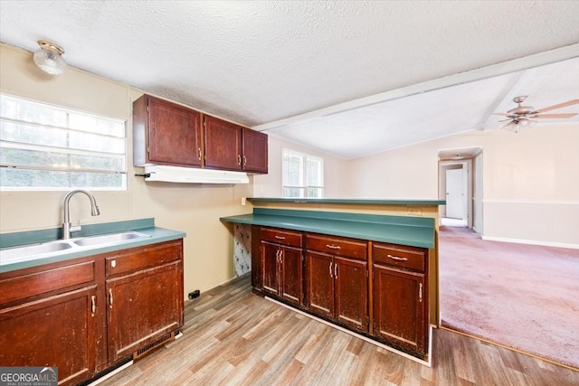 kitchen with light hardwood / wood-style floors, a textured ceiling, and lofted ceiling with beams