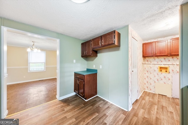 kitchen with light wood-type flooring, an inviting chandelier, and a textured ceiling