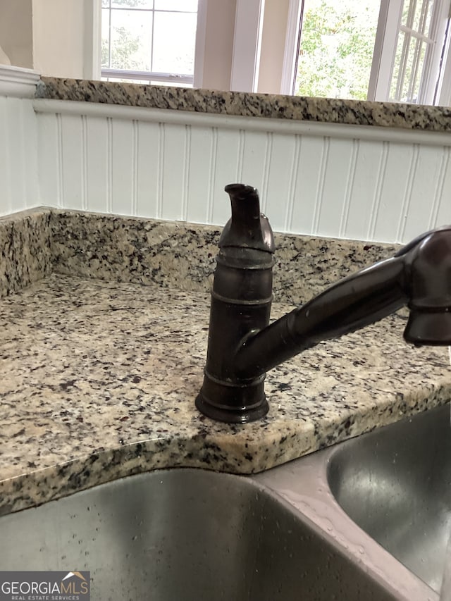 interior details with light stone countertops, sink, and white cabinets