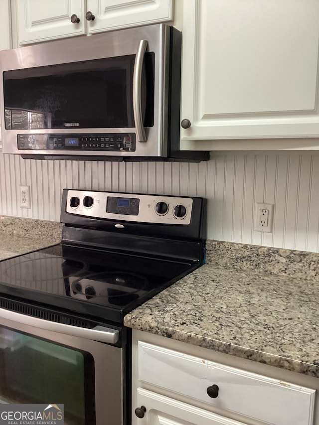 kitchen with white cabinets, light stone counters, and stainless steel appliances