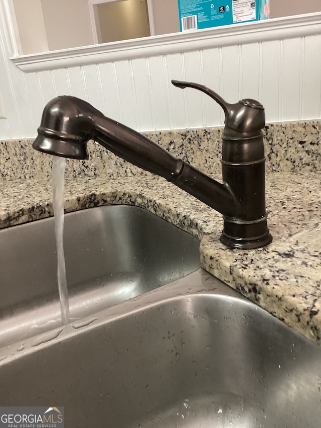 details with light stone countertops, white cabinetry, and sink