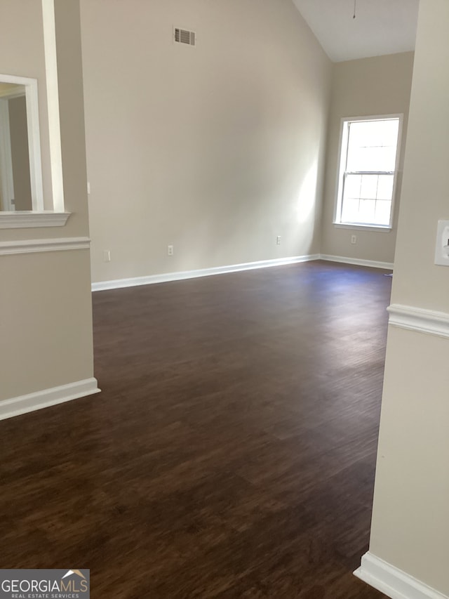 empty room featuring vaulted ceiling and dark hardwood / wood-style flooring