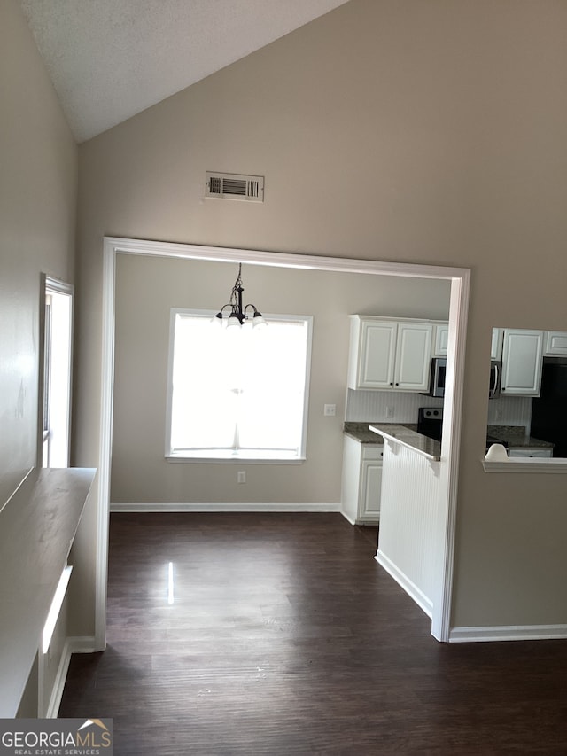 unfurnished living room with high vaulted ceiling, an inviting chandelier, and dark hardwood / wood-style flooring