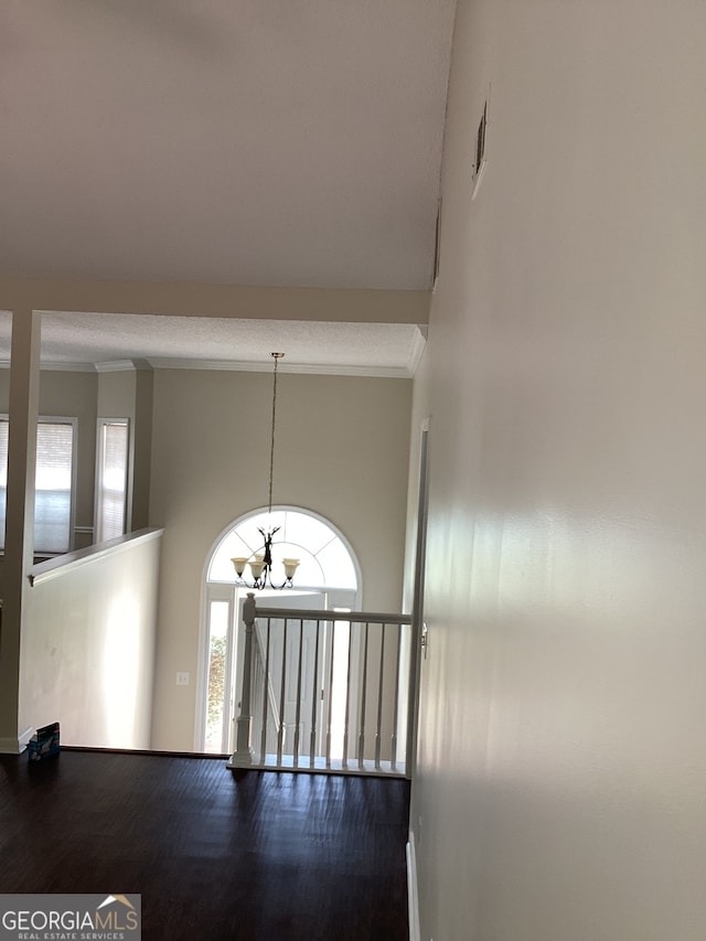 hall with hardwood / wood-style floors, a notable chandelier, and crown molding