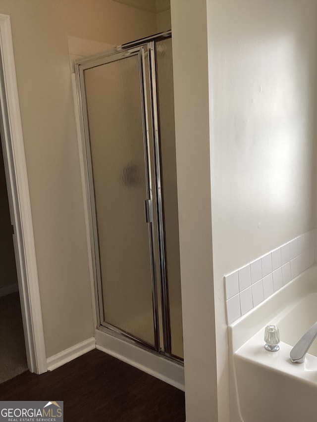 bathroom with hardwood / wood-style floors and independent shower and bath