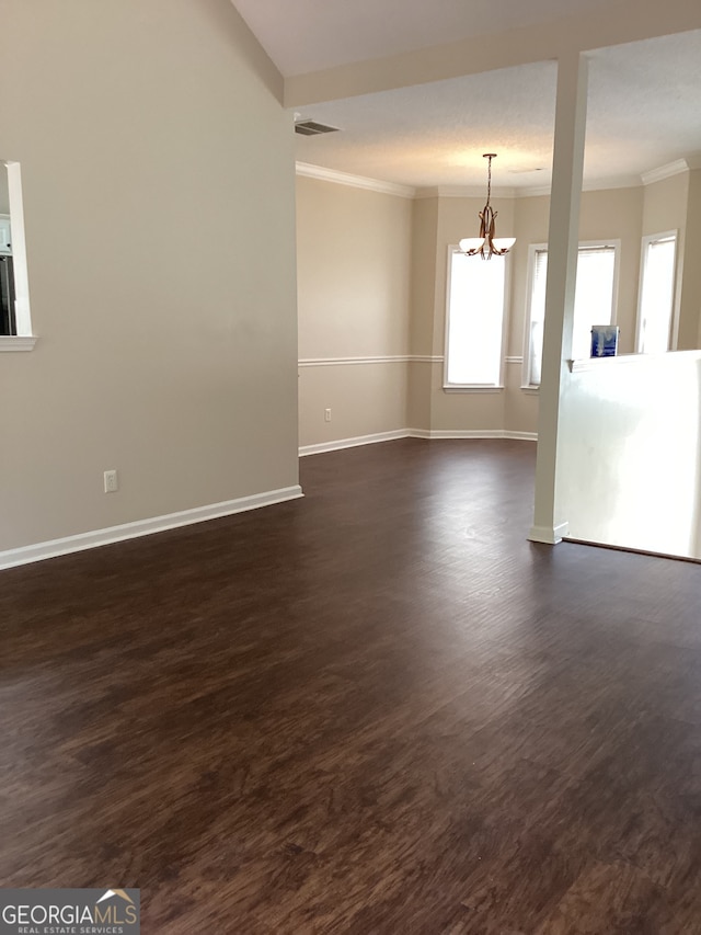 empty room with ornamental molding, a notable chandelier, and dark hardwood / wood-style floors