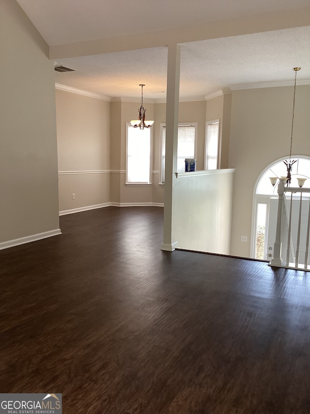 unfurnished room featuring a notable chandelier, a healthy amount of sunlight, and dark hardwood / wood-style floors