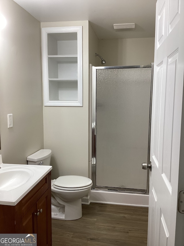 bathroom featuring vanity, hardwood / wood-style flooring, toilet, and a shower with shower door