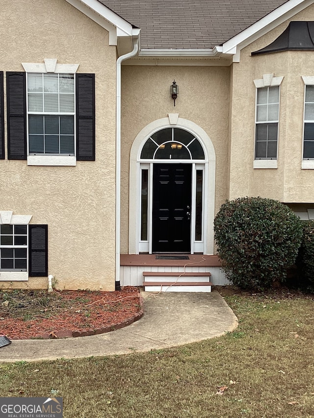 property entrance with a lawn