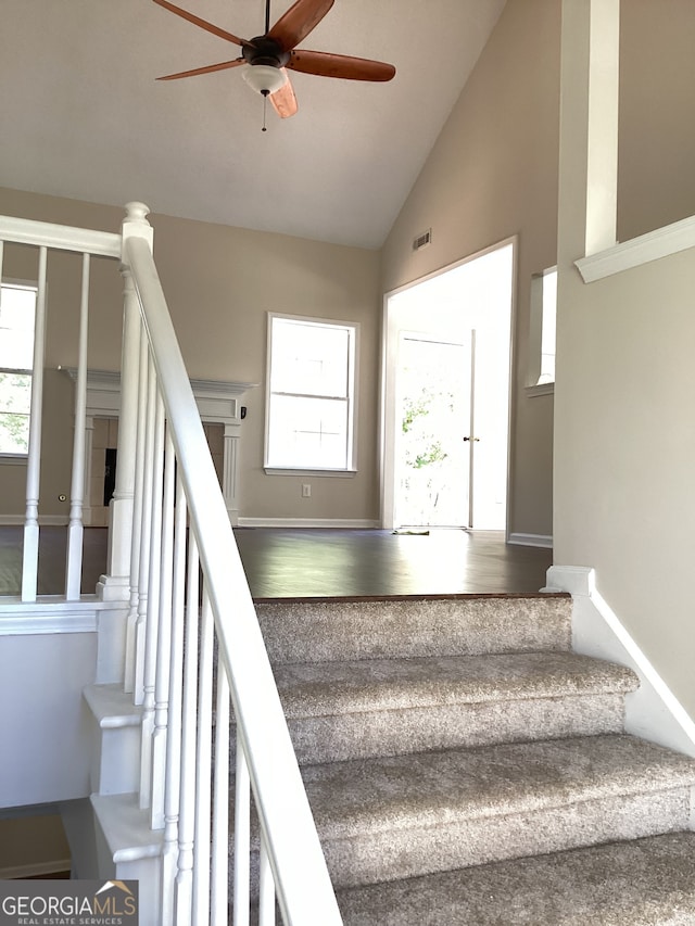 staircase featuring hardwood / wood-style floors, ceiling fan, and high vaulted ceiling