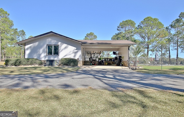 view of property exterior featuring a carport, gravel driveway, cooling unit, and fence