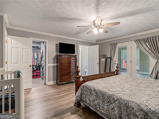 bedroom featuring light hardwood / wood-style floors, ornamental molding, ceiling fan, a spacious closet, and a closet